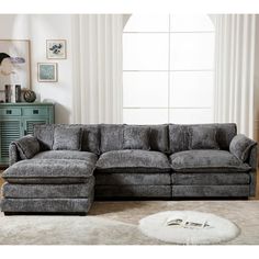 a living room with a gray sectional couch and white rug in front of the window