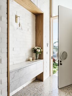 an open door leading to a room with white brick walls and flooring on both sides