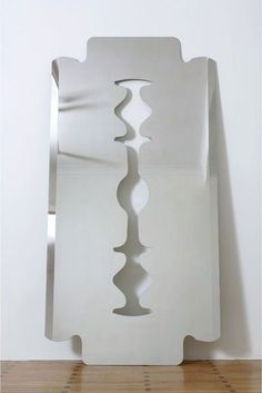 a white sculpture sitting on top of a wooden floor next to a wall mounted mirror