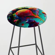 a colorful stool with black legs and a round seat cover on it's back