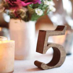 the number five is made out of wood and sits next to a vase with flowers