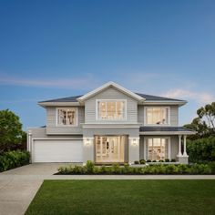 a two story house with an attached garage and large front yard area in the evening