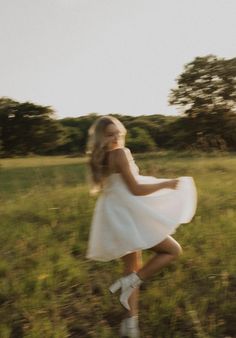 a girl in a white dress is running through the grass