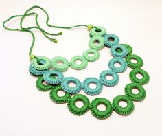 a green and blue necklace on a white surface