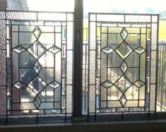 two stained glass windows sitting on top of a window sill next to a brick wall