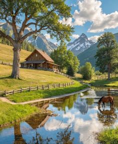 a horse drinking water from a pond in front of a mountain range with a log cabin