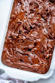 a white dish filled with chocolate frosting on top of a table