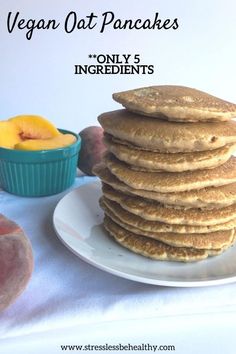 a stack of pancakes sitting on top of a white plate next to a bowl of fruit