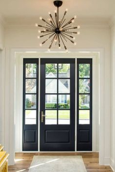 a black front door with two sidelights and a white rug on the floor next to it