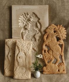 three carved wooden plaques sitting next to each other on top of a cloth covered surface