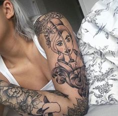 a woman laying on top of a bed next to a white pillow covered in tattoos