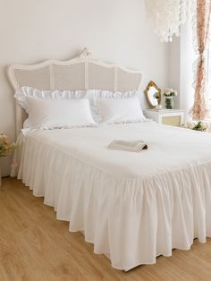 a white bed with ruffled bedspread and pillows