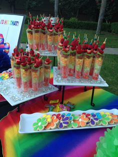 there are many desserts on the table with rainbow colors and strawberries in them