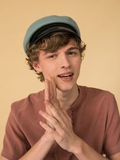 a young man wearing a hat and making a hand gesture