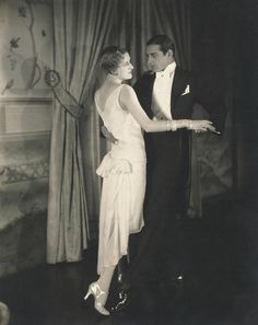 an old black and white photo of a man and woman in formal dress dancing together