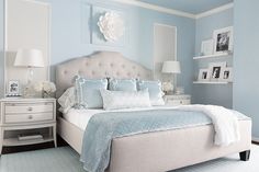 a bedroom with light blue walls and white furniture, including a large bed in the center