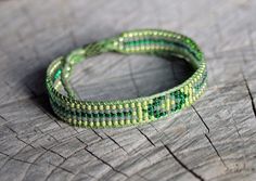 two green beaded bracelets sitting on top of a piece of wood