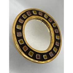 a gold and black circular mirror sitting on top of a table