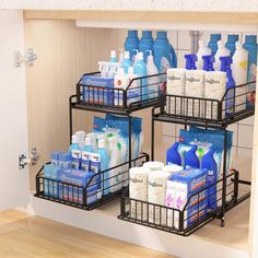 three metal baskets filled with toiletries on top of a wooden floor next to a sink