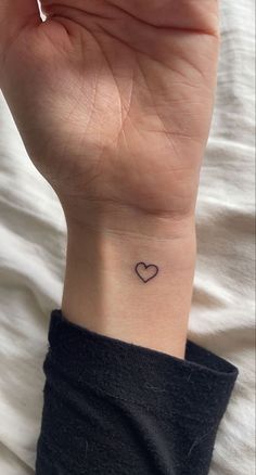 a woman's wrist with a small heart tattoo on the left side of her arm