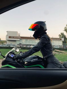 a person riding on the back of a motorcycle in front of a building with grass