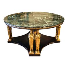 a marble top coffee table with two golden statues on it's legs and an intricately carved base