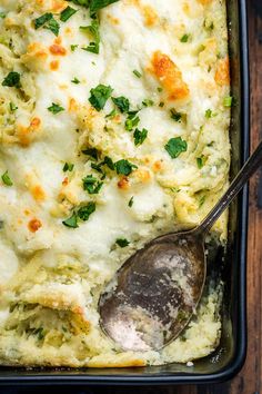 a casserole dish with broccoli and cheese in it, on a wooden table