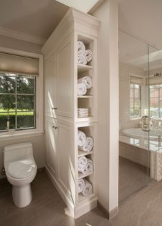 a bathroom with white towels stacked on the shelves