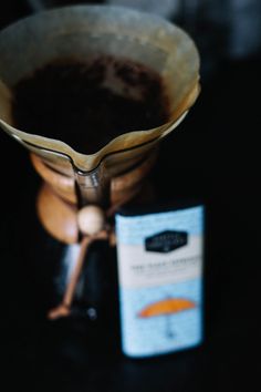 a coffee pot with some liquid in it next to a small packet of tea on a table