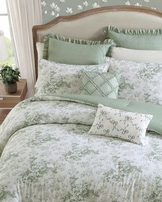 a bed with green and white comforters in a bedroom