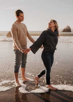 a man and woman holding hands on the beach