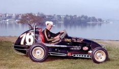 a man sitting in an old fashioned race car with numbers painted on the front and side