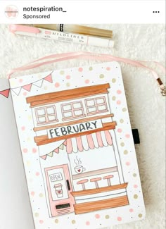 an open notebook with a drawing of a coffee shop on the front and pink polka dots around it