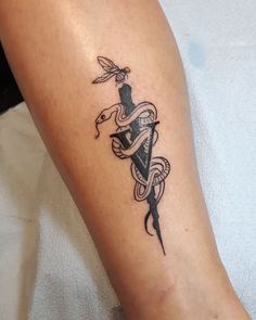 a tattoo on the leg of a person with a snake and dagger in its hand