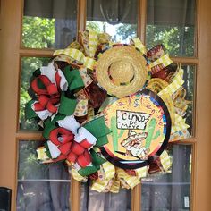 a yellow and red wreath with a cowboy hat on it sitting in front of a window