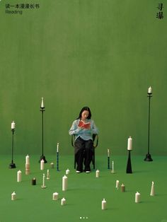 a woman is sitting in a chair surrounded by candles and other small objects on the ground