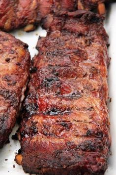 two pieces of steak sitting on top of a white plate