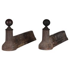 two old rusted metal brackets with wooden knobs on each end and an iron ball at the top