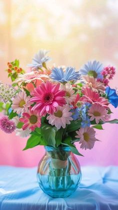 a vase filled with lots of colorful flowers on top of a blue cloth covered table