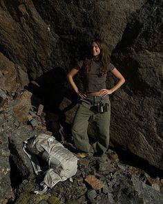 a woman standing on top of a pile of rocks next to a rock climbing device