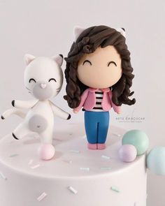 a white cake topped with a figurine of a girl and cat