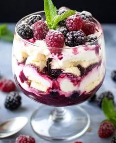 a dessert in a glass with berries and ice cream on top, garnished with mint