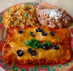 an enchilada with black olives, rice and meat on a plate