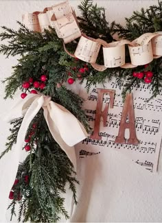 a christmas wreath with music notes and holly garland hanging on the wall next to it