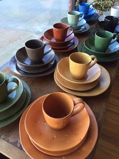 a table topped with lots of different colored cups and saucers on top of plates