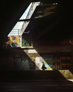 a person walking down a street under a bridge