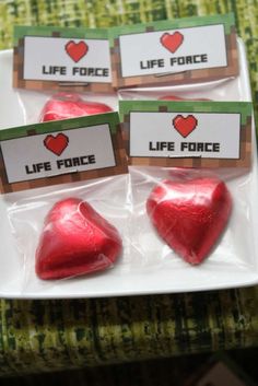 four red heart shaped candies sitting on top of a white plate next to each other