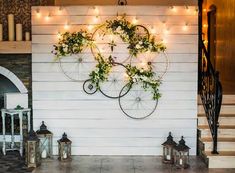 there are two bicycles hanging on the wall with plants growing out of it and lights strung from them