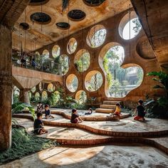 children are sitting on the ground in an open area with circular windows and plants growing inside