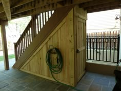 a wooden shed with a horse shoe hanging on the wall and a hose connected to it